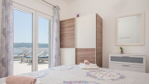 A bedroom with a bed, a nightstand, a mirror, and a view of a pool area. - Beachfront villa Mihovil w. beach access (Kastela)
