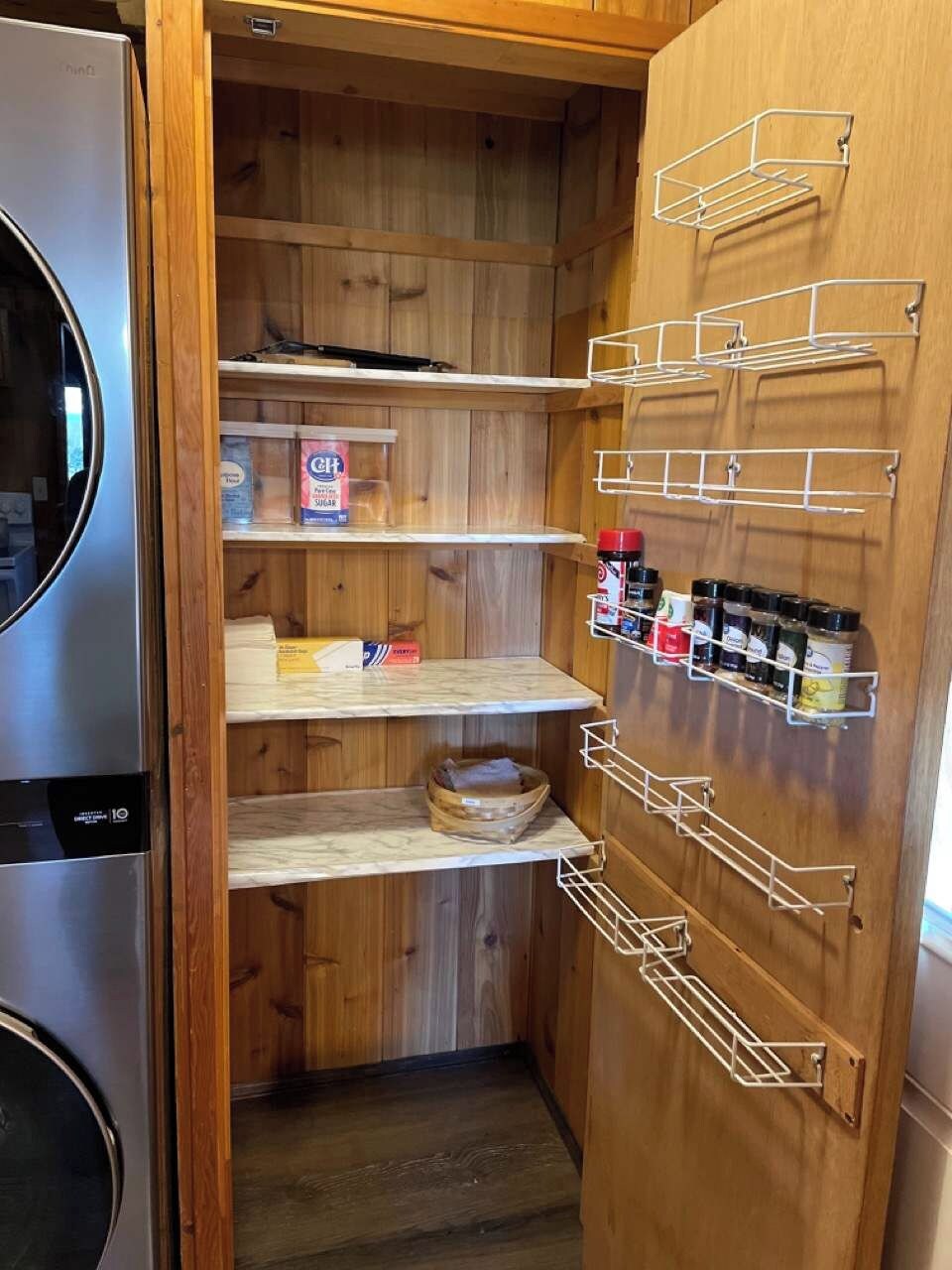 Una cocina compacta con armarios de madera, un refrigerador empotrado y un estante para especias en la pared.
