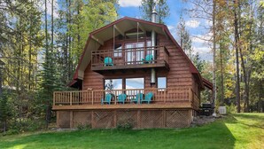 A cabin with a balcony, a deck, and a chimney.