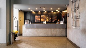 A reception desk with a modern design, a large abstract painting on the wall, and a metal ladder on the right.