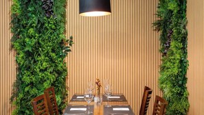 A dining area with a wooden table and chairs, surrounded by vertical green plant walls.