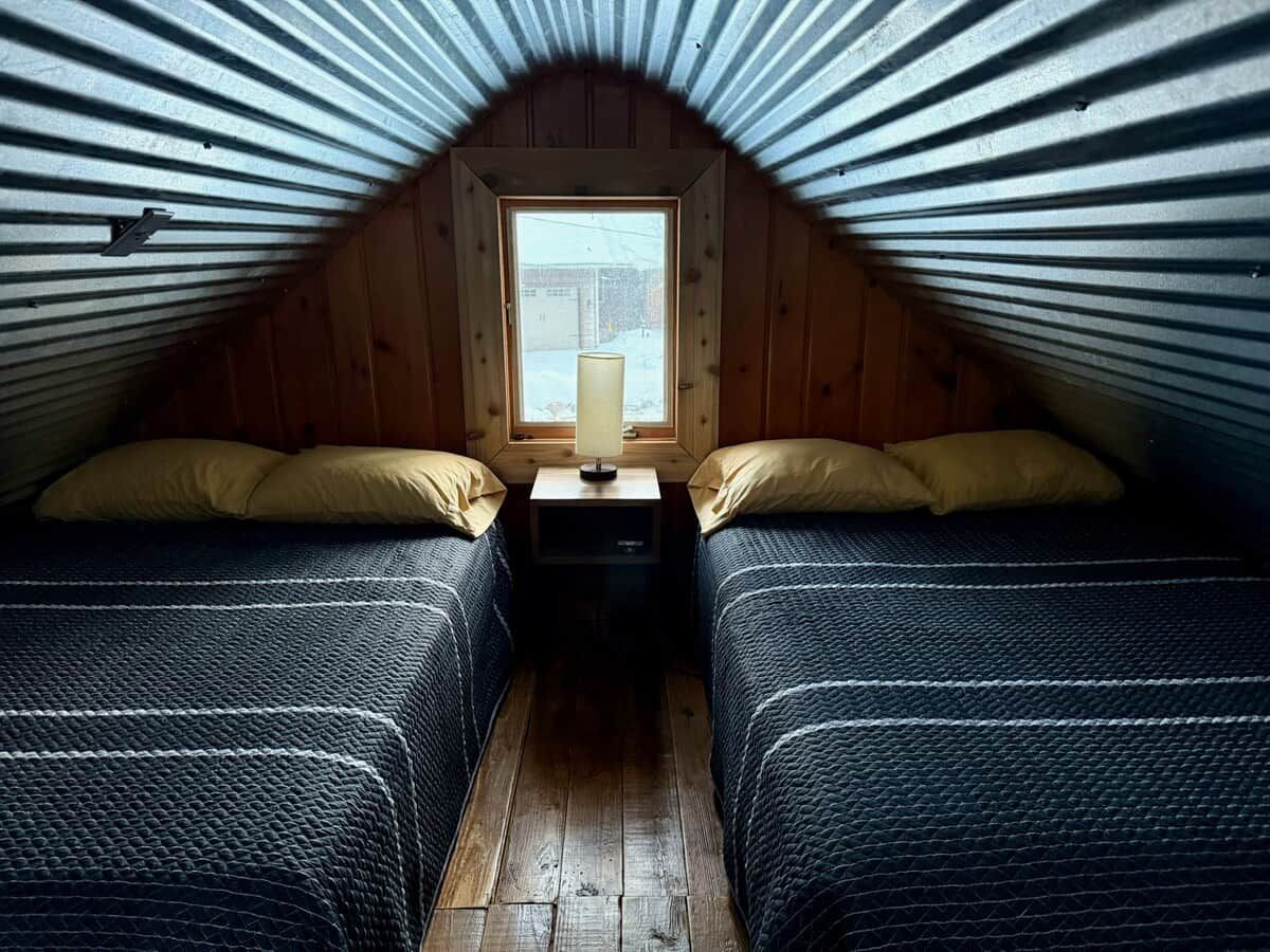 Ein kleines Schlafzimmer im Dachgeschoss mit zwei Betten, einem Nachttisch und einem Fenster.