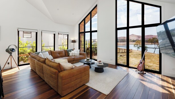 Una sala de estar moderna con un amplio sofá modular, una mesa de centro y un televisor montado en la pared.