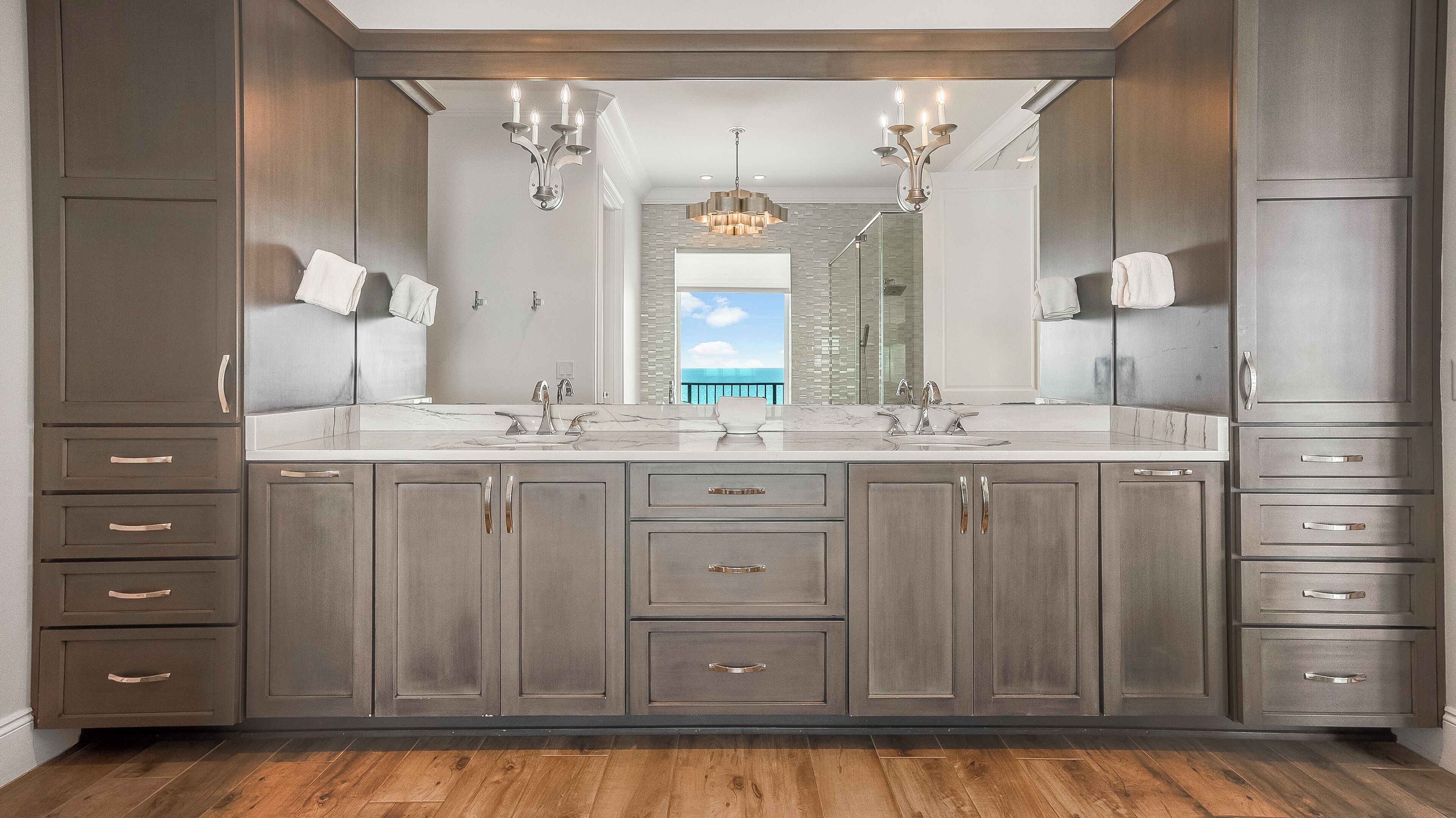 A modern bathroom with a large vanity, double sinks, and a view of the ocean.