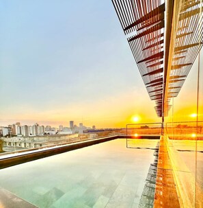 Un edifici modern amb façana de vidre i una piscina reflectant a la part frontal.
