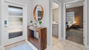 Un couloir avec une console en bois, un miroir et une porte dont les panneaux sont en verre dépoli.
