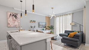 Une cuisine moderne avec un îlot central, un canapé gris et un coin repas.