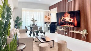 A modern living room with a TV, sofa, coffee table, and ottomans.