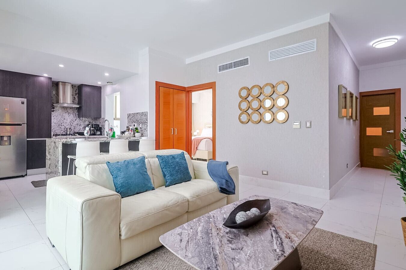 Una sala de estar moderna con un sofá, una mesa de centro y una cocina al fondo.