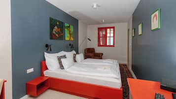 Un dormitorio moderno con un cabecero rojo, una cama individual, una mesita de noche, una silla, un escritorio y una ventana con detalles en rojo.