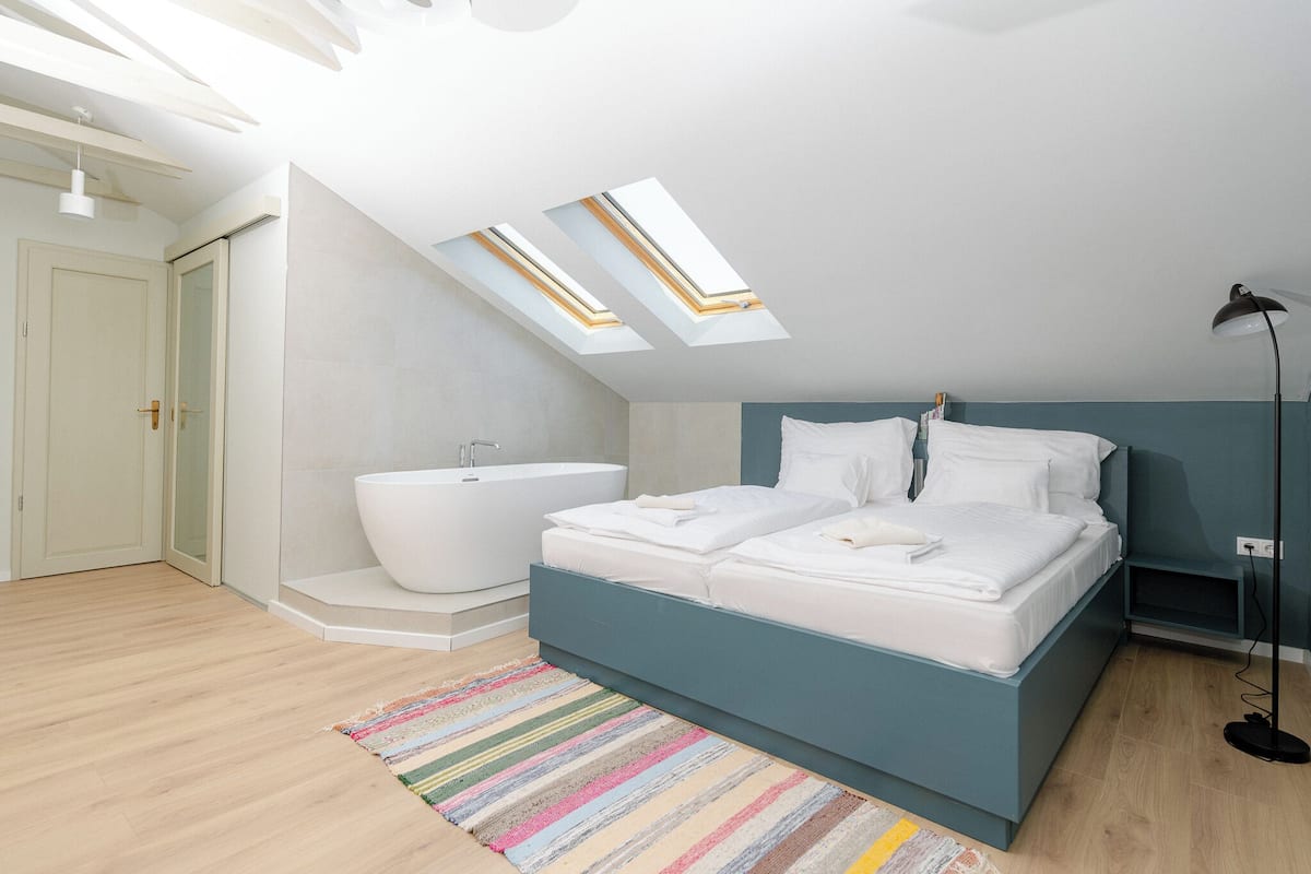Un dormitorio con tragaluces, bañera y lámpara de noche.