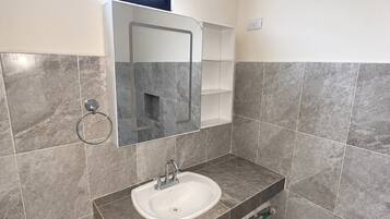 A bathroom with a white sink, a mirror, and grey tiled walls.