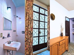 A bathroom with a sink, mirror, and shower.