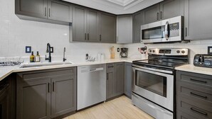 Una cocina moderna con armarios grises, un horno de acero inoxidable, un microondas y un lavavajillas.