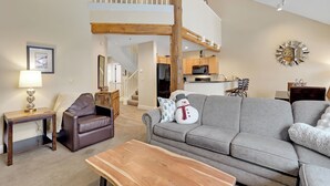 A spacious living area with a grey sofa, a wooden coffee table, and a brown leather chair. A snowman decoration is on the sofa. - Charming Mountain Retreat (Keystone)