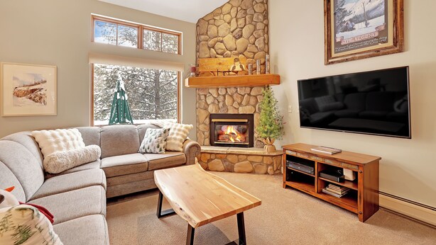 A cozy living room with a stone fireplace, a large flat-screen TV, and a comfortable sofa. - Charming Mountain Retreat (Keystone)