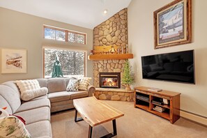 A cozy living room with a stone fireplace, a large flat-screen TV, and a comfortable sofa. - Charming Mountain Retreat (Keystone)