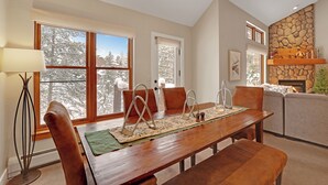 A dining area with a wooden table, chairs, and a fireplace. - Charming Mountain Retreat (Keystone)