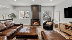 A modern living room with leather sofas, a fireplace, and a large TV.
