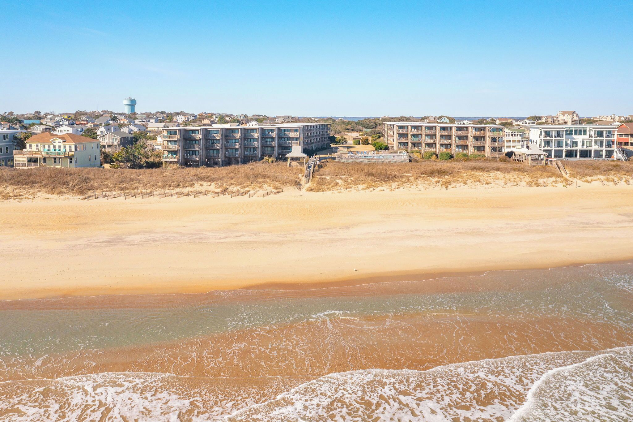 Ein Strandhotel mit mehreren Gebäuden, einem Sandstrand und einem Wasserturm im Hintergrund.