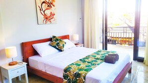 Quarto de hotel com uma cama, duas mesas de cabeceira, um criado-mudo, uma janela com vista e um quadro na parede.