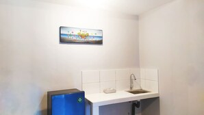 Um banheiro com pia branca, um espelho pequeno e um quadro com pessoas segurando placas na parede.