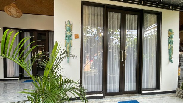 Um saguão de hotel com uma porta de entrada grande, um tapete de boas-vindas e arte decorativa nas paredes.