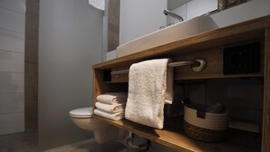 Un baño moderno con tocador de madera, inodoro y cubo de basura.