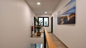 Un interior moderno con una escalera de madera, una planta en maceta y un ventanal con vistas.