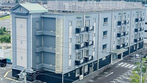 Un edificio de varios pisos con techo plano, varios balcones y una antena parabólica en el techo.