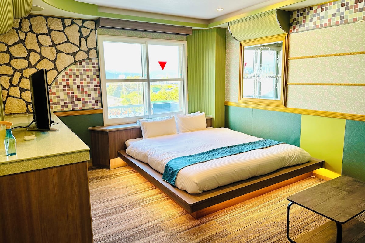 A modern bedroom with a bed, bedside table, and a window with a view.
