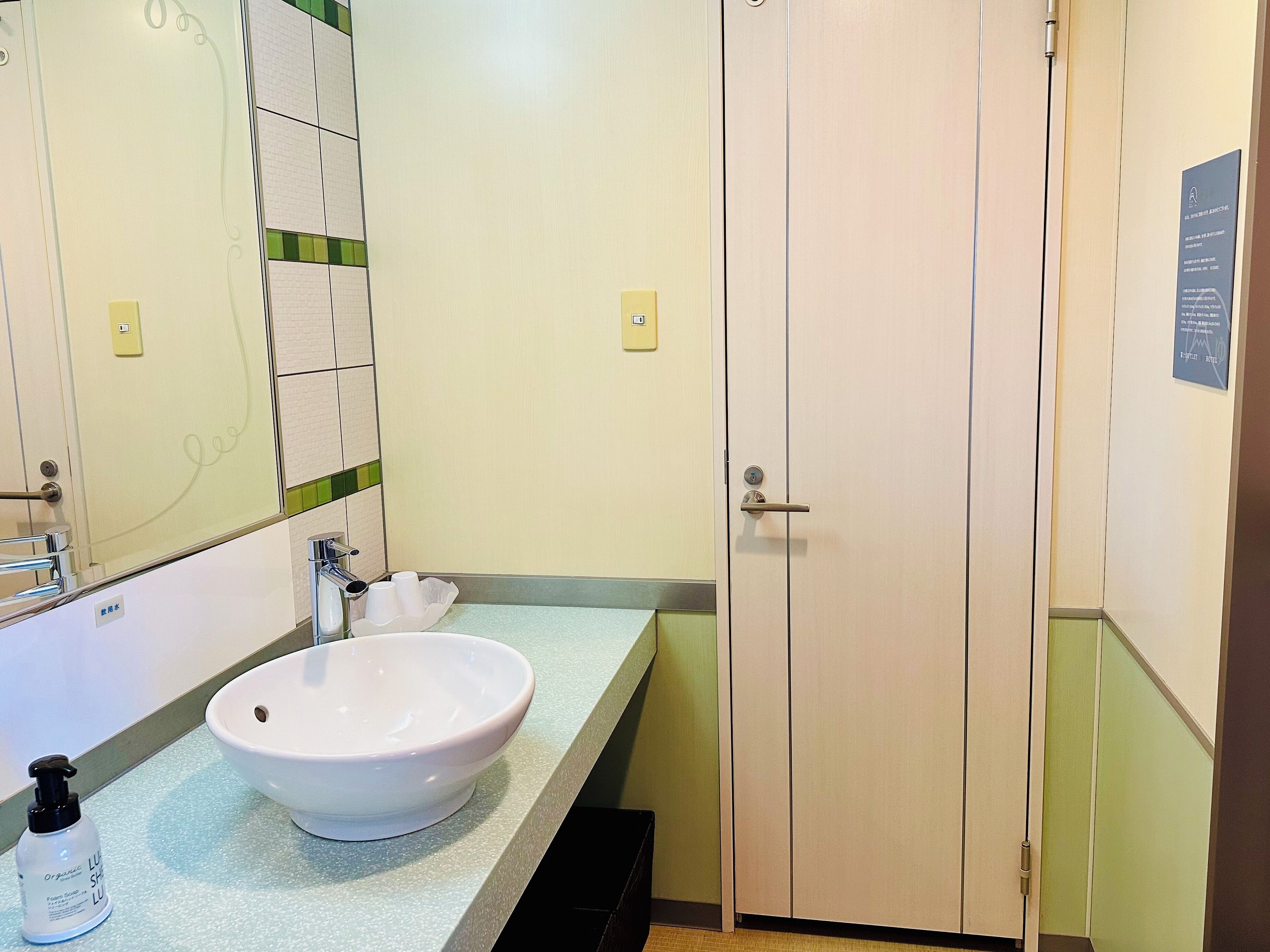 A bathroom with a white sink, a mirror, and a door.