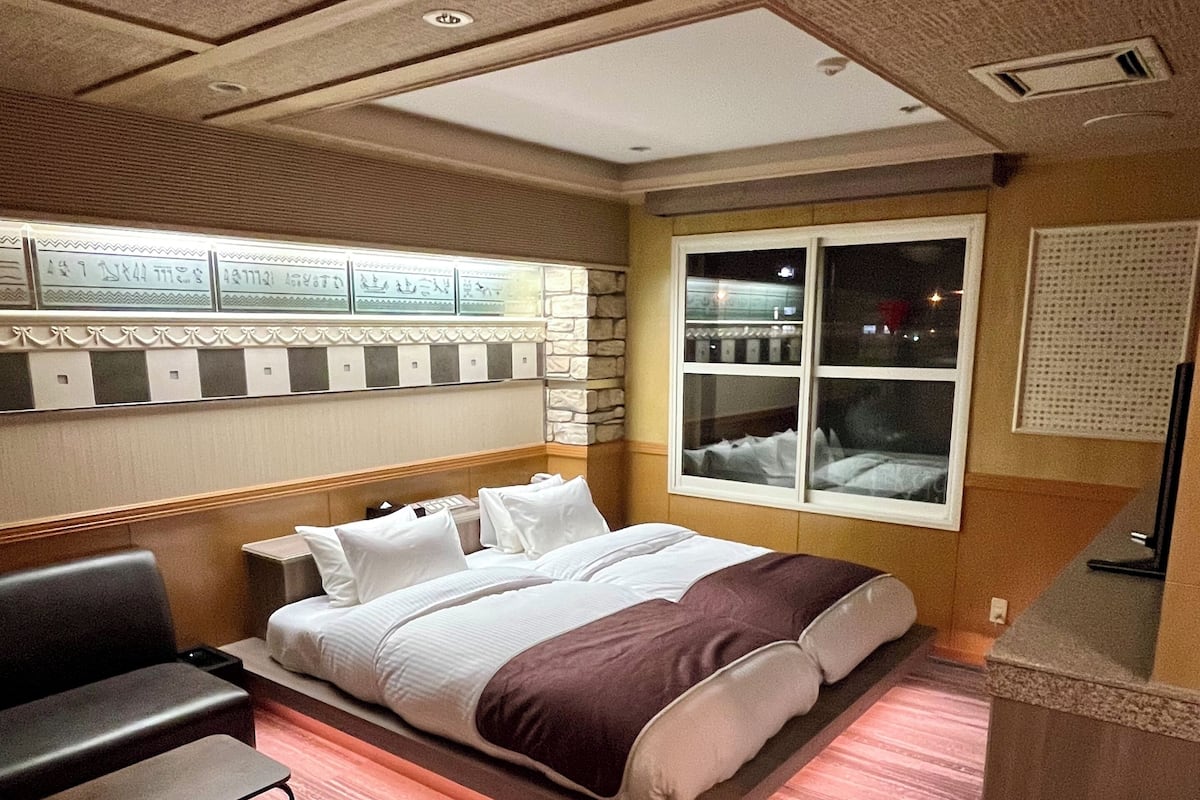 A hotel room with a bed, a desk, and a seating area.