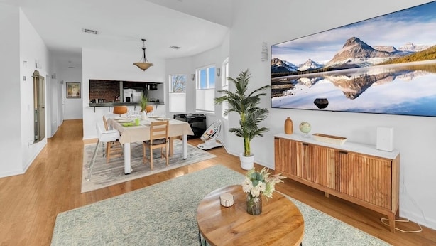 Een ruime woonkamer met een groot flatscreen televisietoestel, een eethoek en een keuken op de achtergrond.