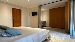 Ein Schlafzimmer mit einem Bett, einem Fernseher, einem Schreibtisch und einem Kleiderschrank.