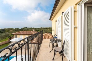 Enjoy the serene view from this balcony with a round table and two chairs, perfect for taking in the lush surroundings.