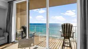 En balkon med havudsigt, et skilt med teksten "Welcome to Cambridge Condo Panama City Beach", og et bord med stole.