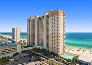 A high-rise hotel with multiple floors, a beach view, and a parking area.