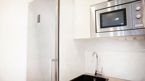 A modern kitchen with a stainless steel refrigerator, a built-in microwave, and a sink with a faucet.