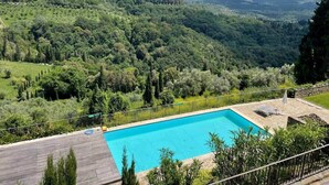A rectangular swimming pool with a stone deck, surrounded by a wooden deck and a metal fence. - La Querciola Castelfalfi Borgo (Castelfalfi)