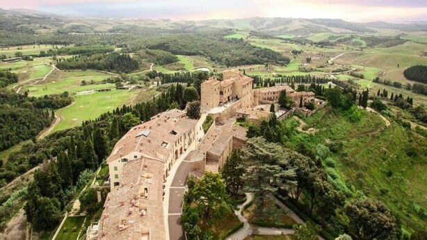 An aerial view of a historic building complex surrounded by lush greenery and rolling hills. - La Querciola Castelfalfi Borgo (Castelfalfi)