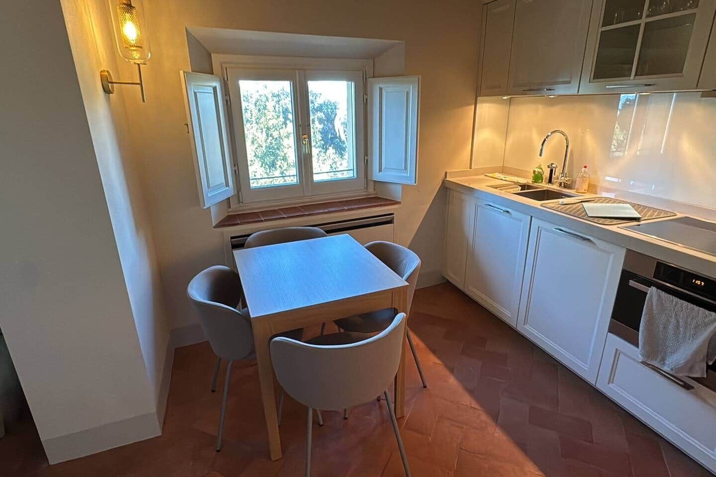 Une cuisine compacte comprenant une table à manger, des chaises, une fenêtre avec vue et un évier.