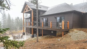A cabin with a covered deck, outdoor seating, and a view of the surrounding forest. - Spacious 2-Level Custom Craftsman Style Lodge w/ Hot Tub, Fire Pit, Clubhouse (Lead)