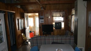 A room with a dining table, chairs, a television, and a sofa. - Affordable Family Fun on the Platte Lakes Van Hammen Cottage #3 (Honor)
