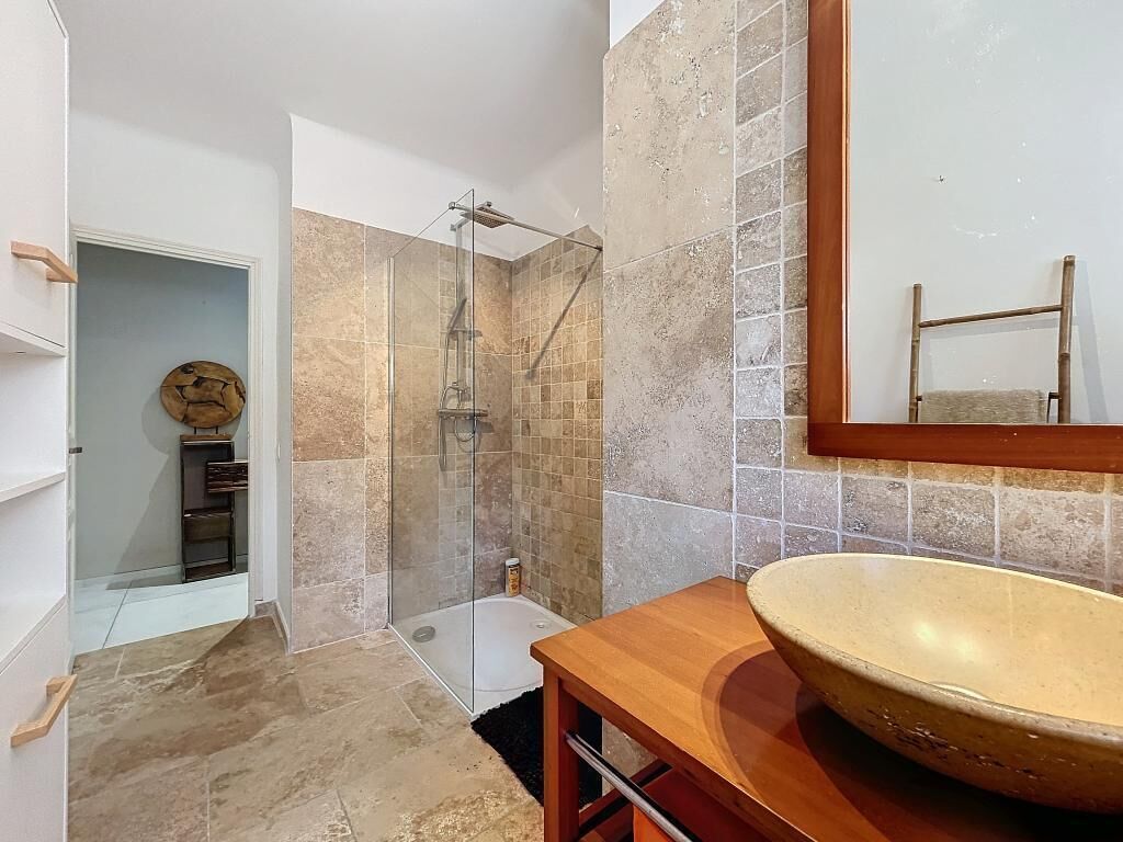 A bathroom with a large sink, a shower, and a mirror.
