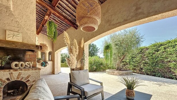 An outdoor patio with a brick fireplace, cushioned seating, and a table with a potted plant. - Family Villa with swimming pool tennis spa (Auribeau sur siagne)
