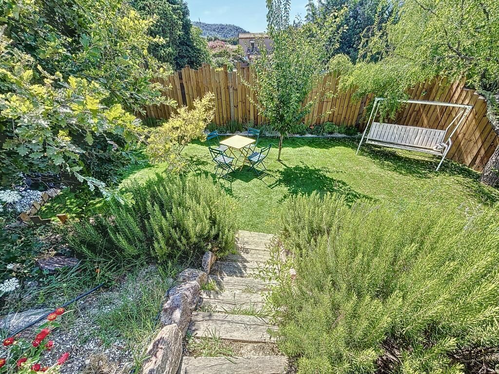 Un jardin avec une clôture en bois, un banc et une table.