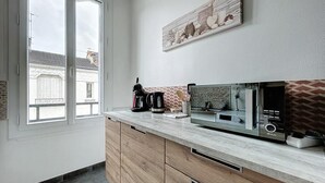 Een moderne keuken met een ingebouwde magnetron, koffiezetapparaat en houten kastjes.