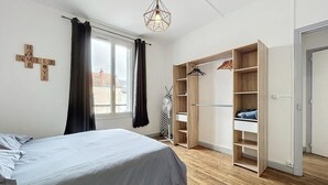 Een slaapkamer met een bed, een kledingkast en een raam met gordijnen.