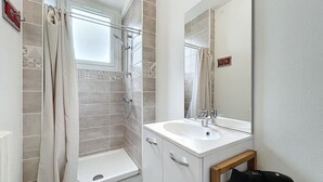 Een moderne badkamer met een douche, een wastafel en een spiegel.